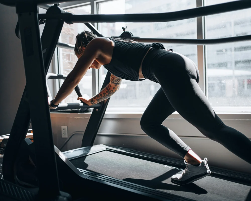 Woman training on a curved treadmill by a window